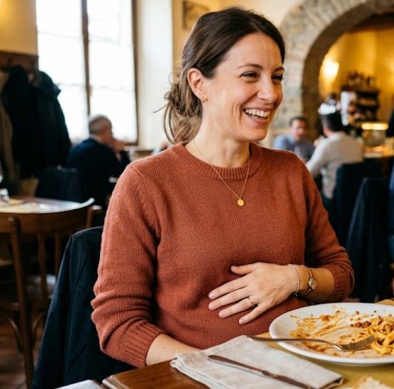 Donna sorridente a tavola al ristorante con una mano sull'addome